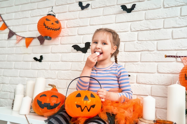 Niña comiendo dulces de un balde de calabaza