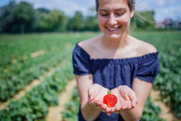 Niña comiendo una fresa mientras recolecta fresas en un campo