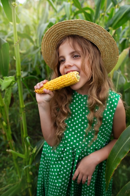 Foto niña comiendo maíz en el campo