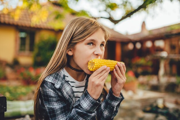 Niña comiendo maíz dulce al aire libre