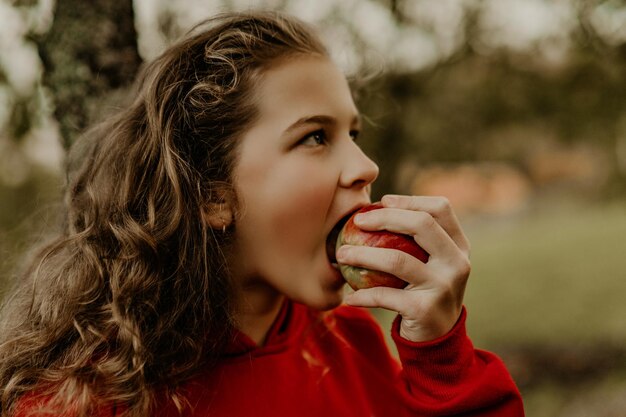 Niña comiendo manzana fresca en la naturaleza