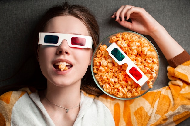 Niña comiendo palomitas de maíz en gafas 3d