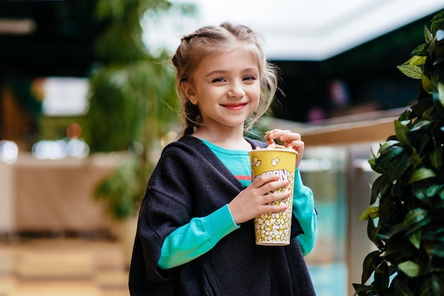 Niña comiendo palomitas de maíz en el interior