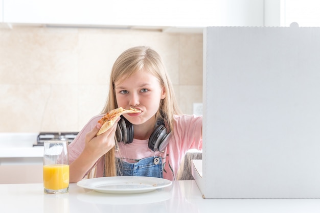 Niña comiendo pizza sentado en la mesa