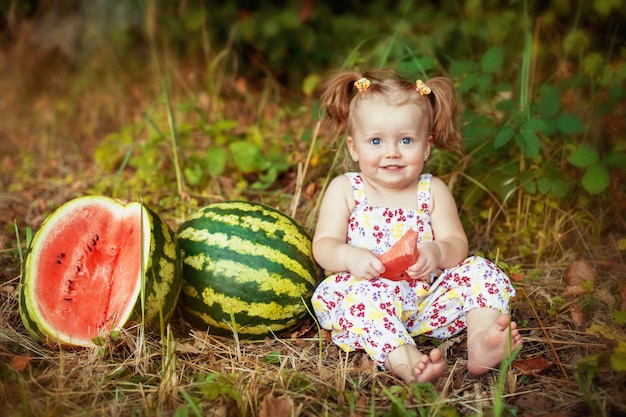 Niña comiendo sandía. El concepto de desarrollo infantil y alimentación saludable.