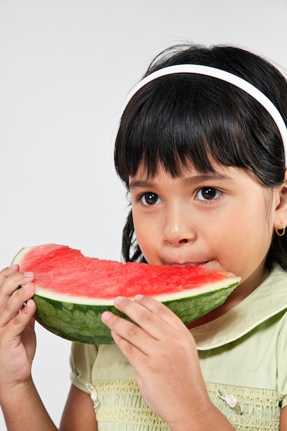 Foto niña comiendo sandía contra un fondo blanco