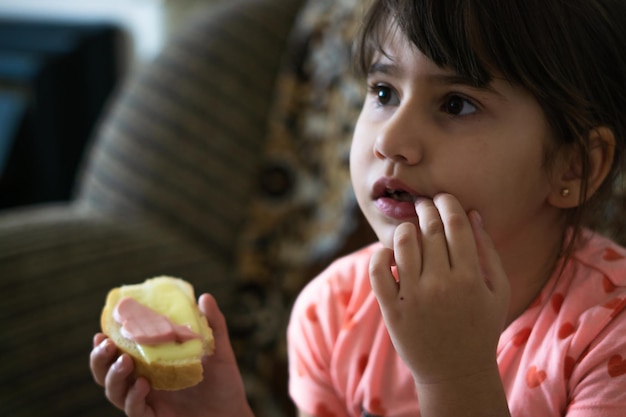 niña comiendo un sándwich sentado en un sillón