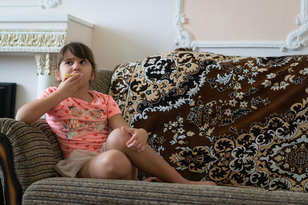 niña comiendo un sándwich sentado en un sillón