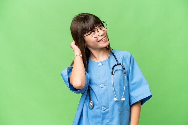 Niña como médico cirujano sobre un fondo clave de croma aislado pensando en una idea