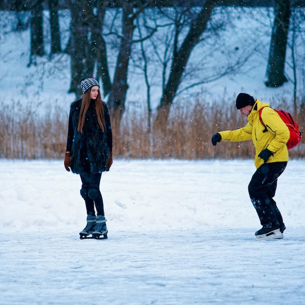 Niña y compañeros de patinaje sobre hielo en la pista de invierno cubierta de nieve en Trakai en Lituania.