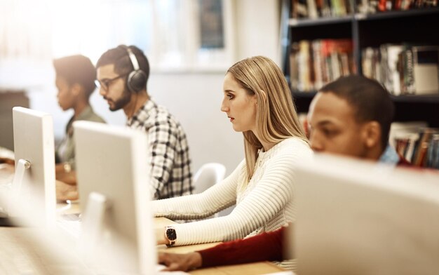 Niña computadora y estudiantes aprendiendo en la biblioteca para el conocimiento de la educación o la preparación de exámenes en la universidad Mujer investigadora universitaria e internet para estudiar notas de proyectos y informe de exámen en línea