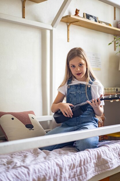 Niña concentrada tocando melodía en el ukelele practicando ejercicio musical disfrutando de estudio educativo