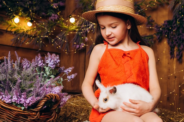 Niña con un conejo en una granja con un trasfondo de heno y lavanda