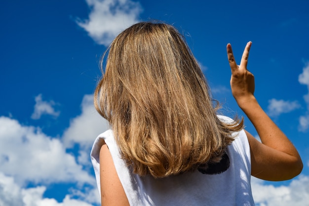 la niña contra el cielo representa una mano de victoria