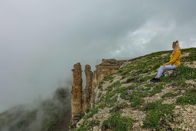 Una niña contra el fondo de dos rocas de monjes en una nube Meseta de Bermamyt Rusia 2021 junio