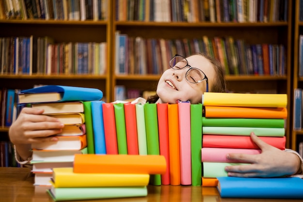 Foto la niña en copas en la biblioteca abraza libros.