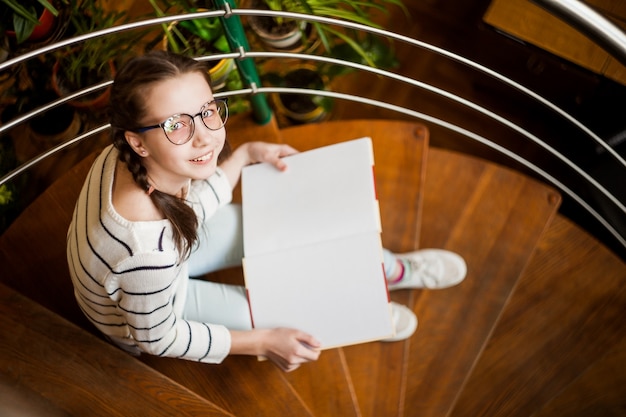 La niña en copas con un libro en sus manos.