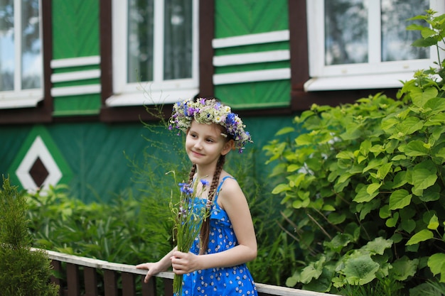 niña en una corona de flores silvestres en el pueblo