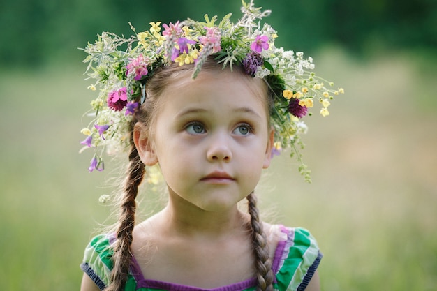 niña en una corona de flores silvestres en verano