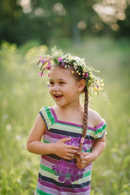 niña en una corona de flores silvestres en verano