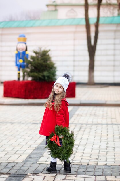 Niña con corona de navidad en la calle