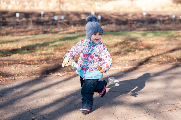 La niña corre al parque de otoño