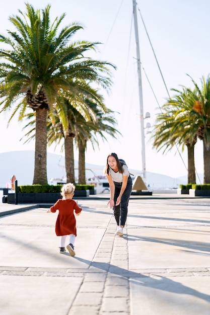 La niña corre a los brazos de su madre en un muelle en un día soleado.