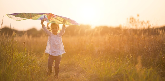 Una niña corre a un campo con una cometa aprende a lanzarla Entretenimiento al aire libre en verano naturaleza y aire fresco Niñez libertad y descuido Un niño con alas es un sueño y una esperanza