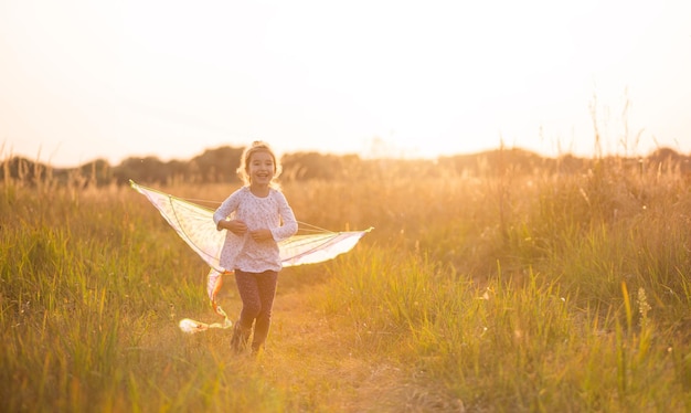 Una niña corre a un campo con una cometa aprende a lanzarla Entretenimiento al aire libre en verano naturaleza y aire fresco Niñez libertad y descuido Un niño con alas es un sueño y una esperanza