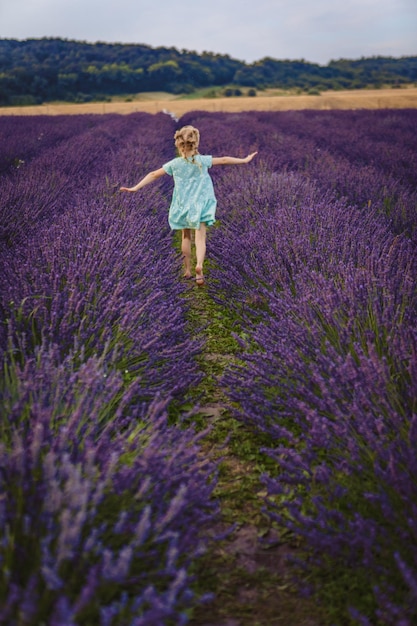 Una niña corre por un campo de lavanda.