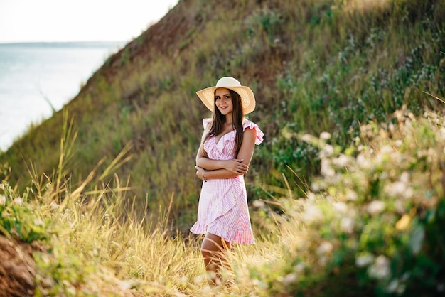 La niña corre por el campo Niña feliz Cabello largo Vestido blanco Un sombrero con ala Ramo de margaritas Una niña en la naturaleza