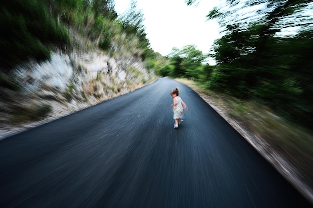 Niña corre en la carretera de montaña Foto borrosa