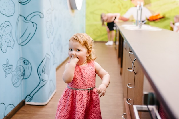 Una niña corre, se escapa de su mamá y juega en la cocina. Niños felices.