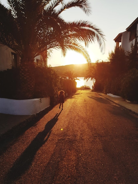 Niña corriendo por la carretera durante la puesta de sol