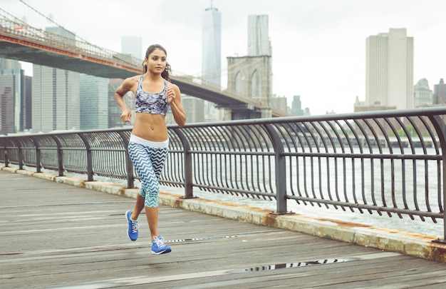 Niña corriendo en el muelle con el horizonte de Nueva York en el fondo