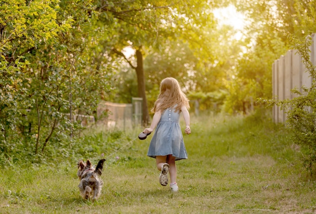 Niña corriendo con el perro en el campo