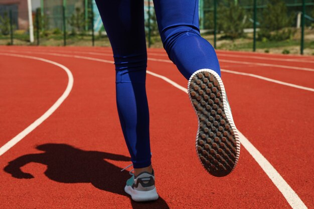 Niña corriendo en la pista de atletismo rojo. Concepto deportivo