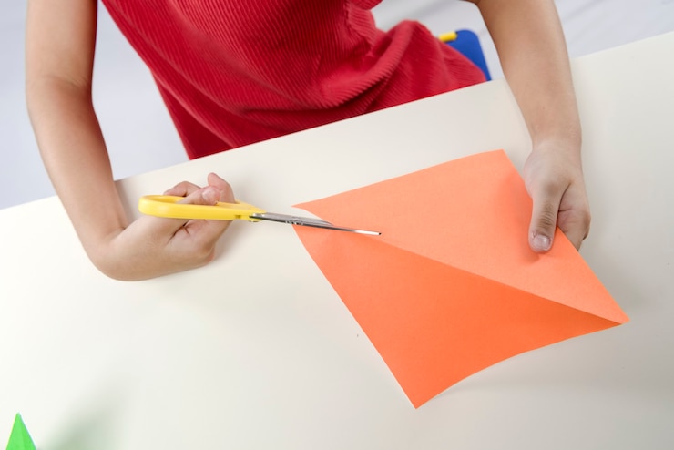 Foto niña cortando un papel aislado sobre fondo blanco.