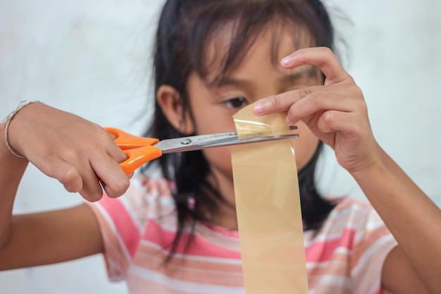 Una niña cortando un trozo de papel con unas tijeras.