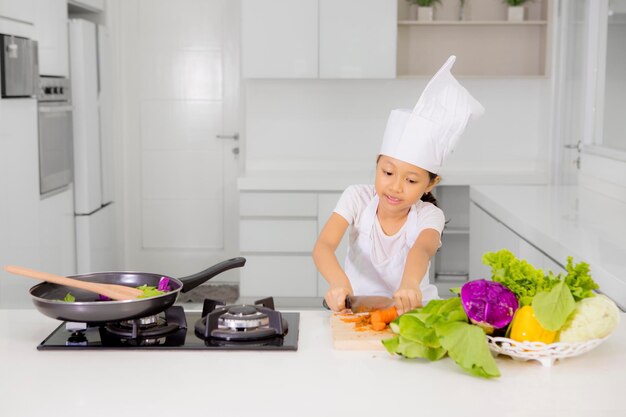 Niña cortando una zanahoria en la cocina