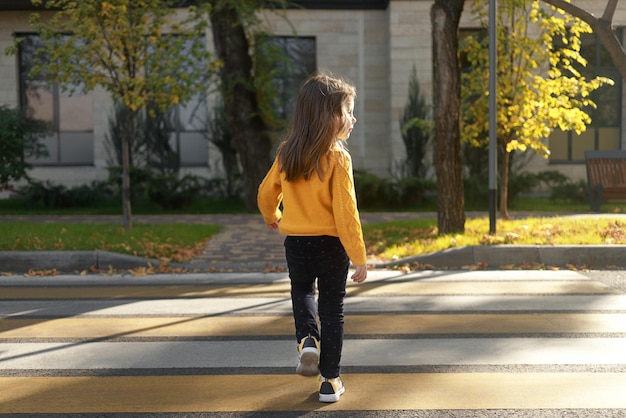 Una niña cruza la calle en un paso de cebra mira a su alrededor