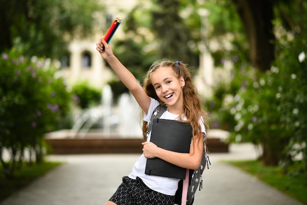 Una niña con un cuaderno y lápices Regreso a la escuela