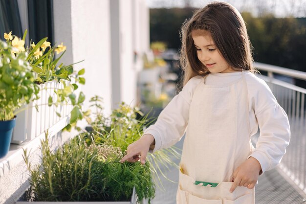 Niña de cuatro años de edad en brillo general de pie por florero y preparándose para aterrizar en el balcón