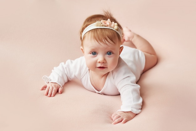 Foto una niña de cuatro meses yace sobre un fondo rosa claro.