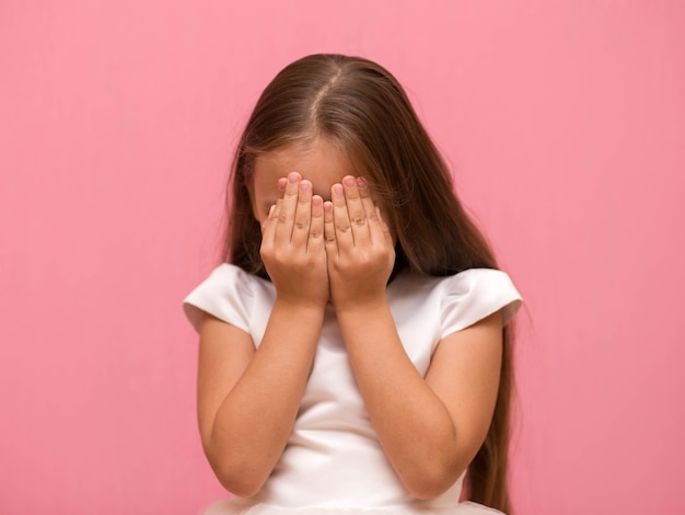 Foto niña cubre su rostro con sus manos