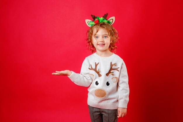 Niña con cuernos de ciervo sobre un fondo rojo, navidad, año nuevo