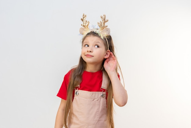 Una niña con cuernos de reno navideño te está escuchando a escondidas.