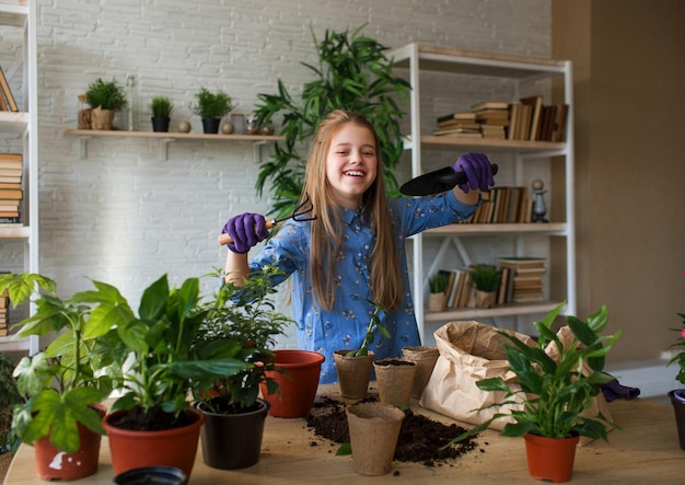 Una niña cuida las flores, mira y admira una flor El concepto de un jardín doméstico