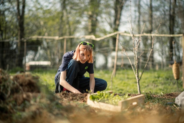 Niña cultivando verduras en el jardín al aire libre en primavera