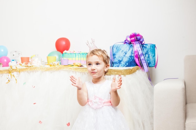 Niña cumpleañera con corona en la cabeza sosteniendo globos de colores. La niña princesa en la fiesta de cumpleaños.
